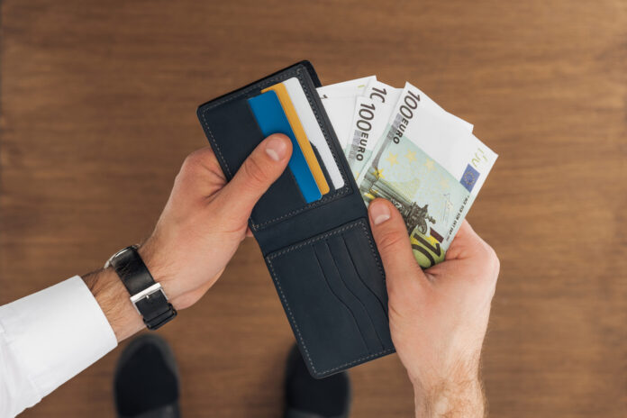 Bovenaanzicht van zakenman die geld uit portomonnee haalt